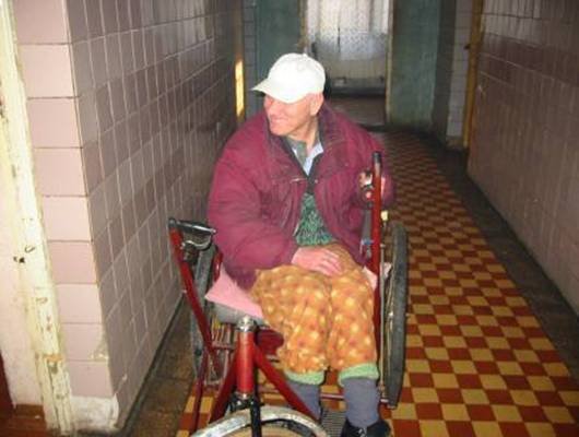 Photo: Hier ist ein Patient mit einem Rollstuhl im Gang der Klinik. Wenn man die Bausubstanz anguckt, sieht ma